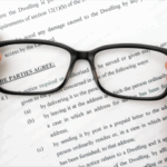 Imagen de unas manos sujetando unas gafas encima de un folio con letras