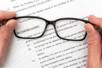 Imagen de unas manos sujetando unas gafas encima de un folio con letras